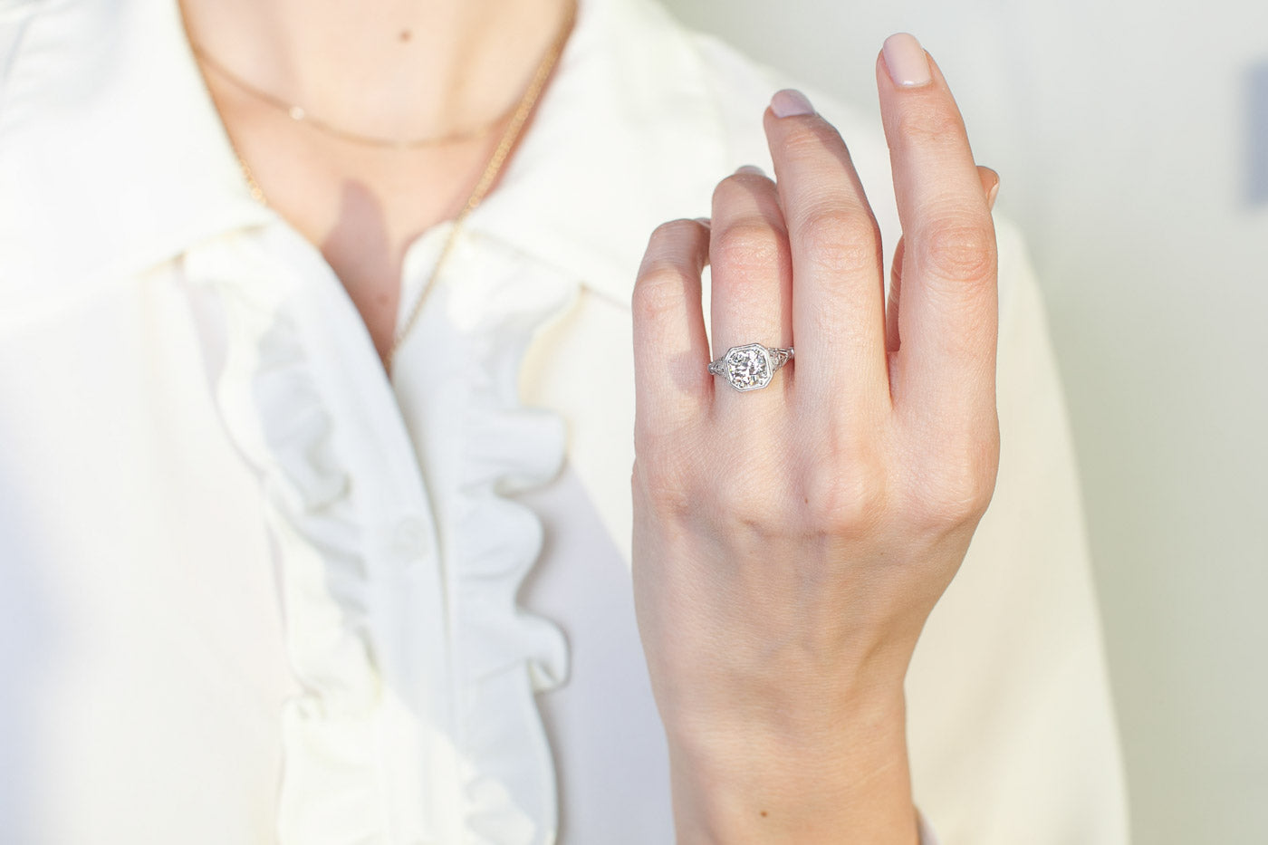 Hand wearing a diamond ring with a blurred background