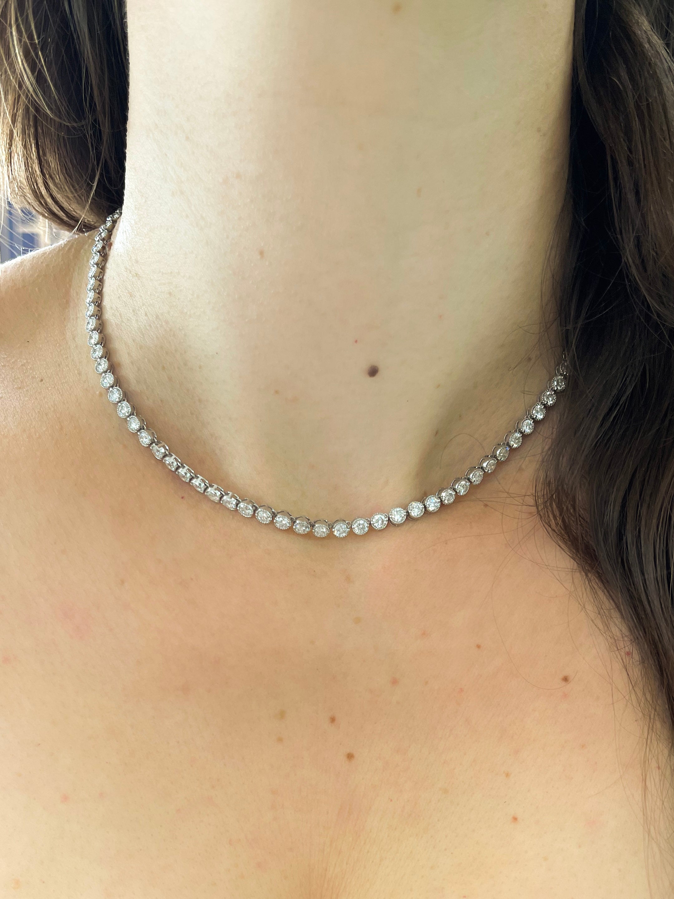 Diamond necklace worn by a person with a blurred background