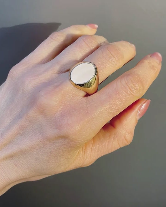 Authentic vintage oval signet ring in polished yellow gold, classic domed face in natural lighting